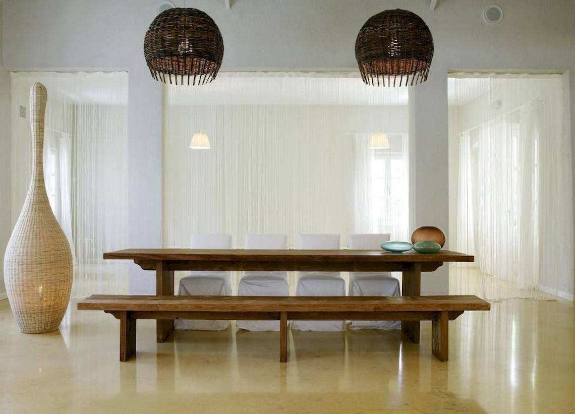 Esszimmer im Doryssa Seaside Resort mit Holztisch, Bänken, Korblampen und weißen Vorhängen.