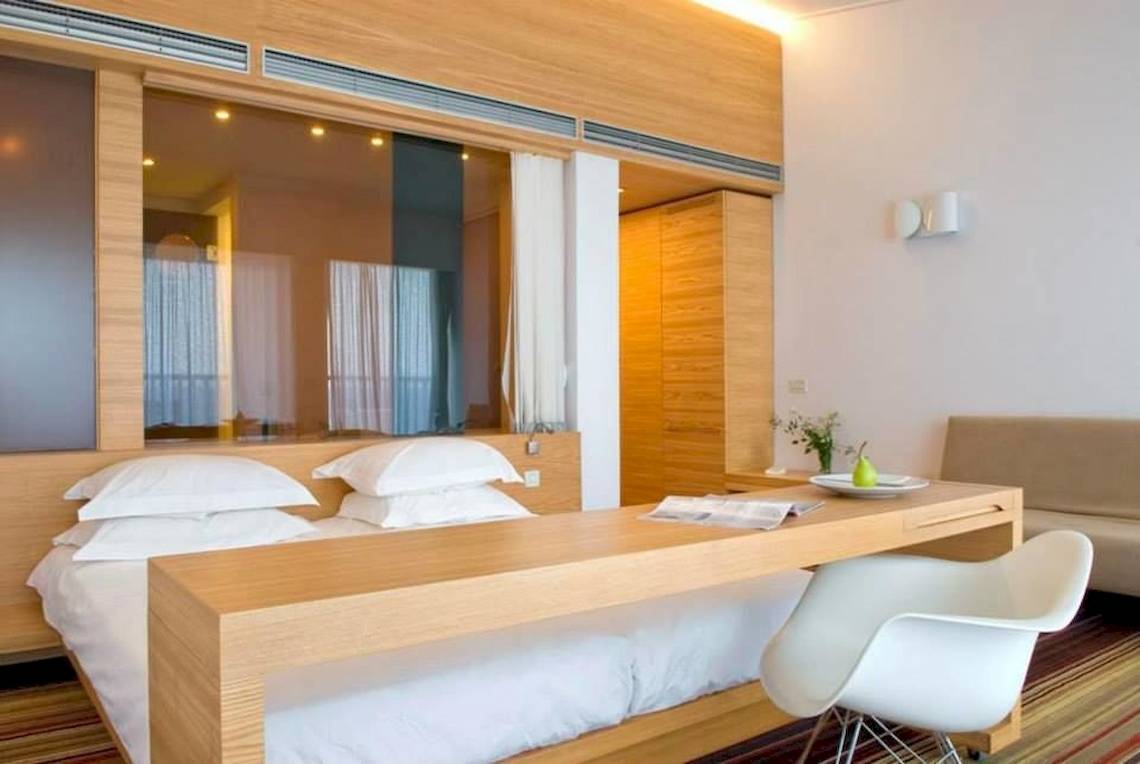 Ein modernes Hotelzimmer im Doryssa Seaside Resort mit einem Bett, Schreibtisch und Couch.