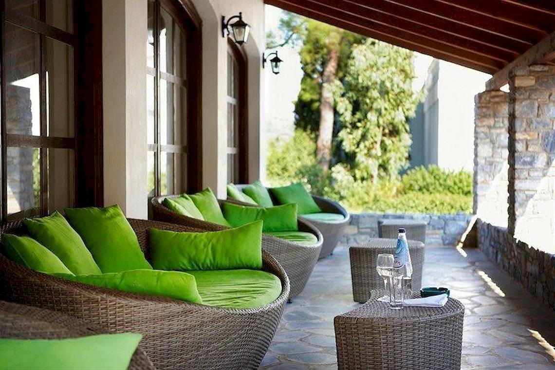 Terrasse des Doryssa Seaside Resort mit grünen Sofas und Kissen.