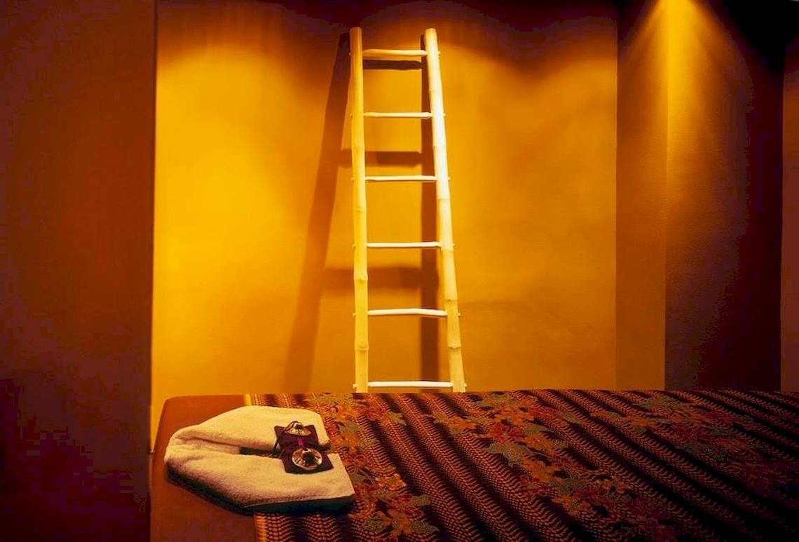 Ein Zimmer im Doryssa Seaside Resort mit einem Bett, einer Leiter und einem Handtuch auf dem Tisch.