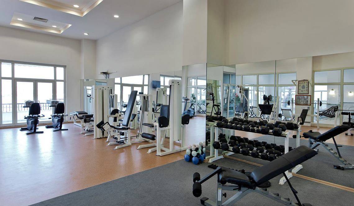 Fitnessstudio im Selectum Colours Bodrum Hotel mit vielen Geräten und großen Fenstern.