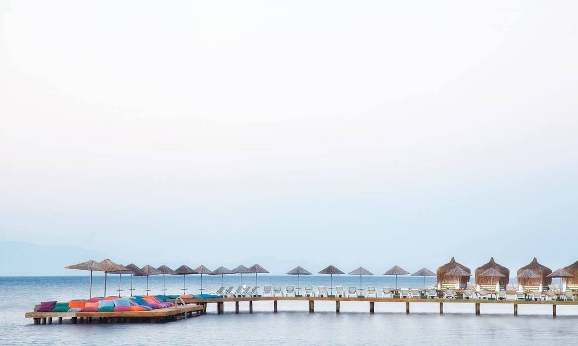 Strandlounge des Selectum Colours Bodrum Hotels mit bunten Kissen und Sonnenschirmen