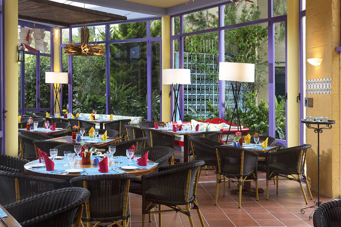 Innenansicht des Dionysos Hotels, Restaurantbereich mit runden Tischen, Stühlen und Lampen.