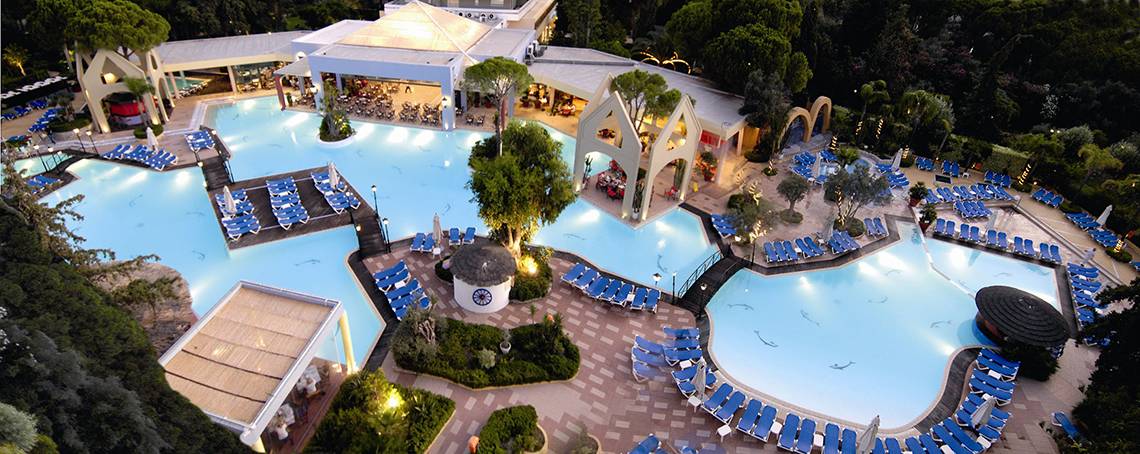 Luftaufnahme des Dionysos Hotels mit Swimmingpool und vielen Liegestühlen.
