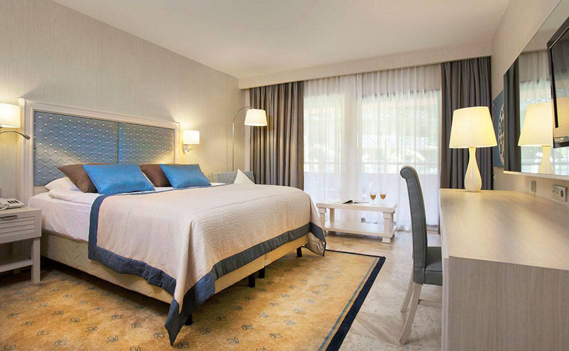 Schlafzimmer im Marti Myra Hotel mit einem großen Bett, Kissen und einem Schreibtisch.