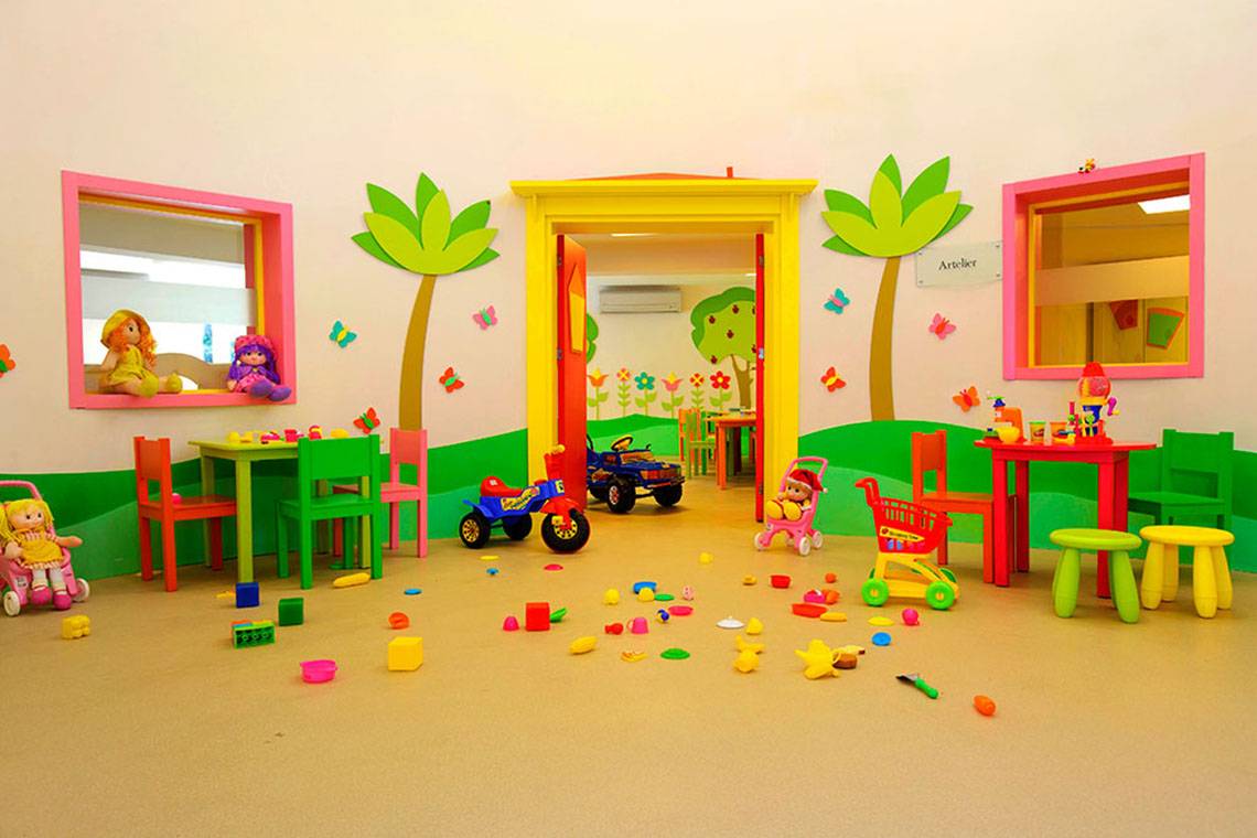 Kinderspielzimmer im Hotel Marti Myra mit bunten Möbeln und Spielzeug auf dem Boden.
