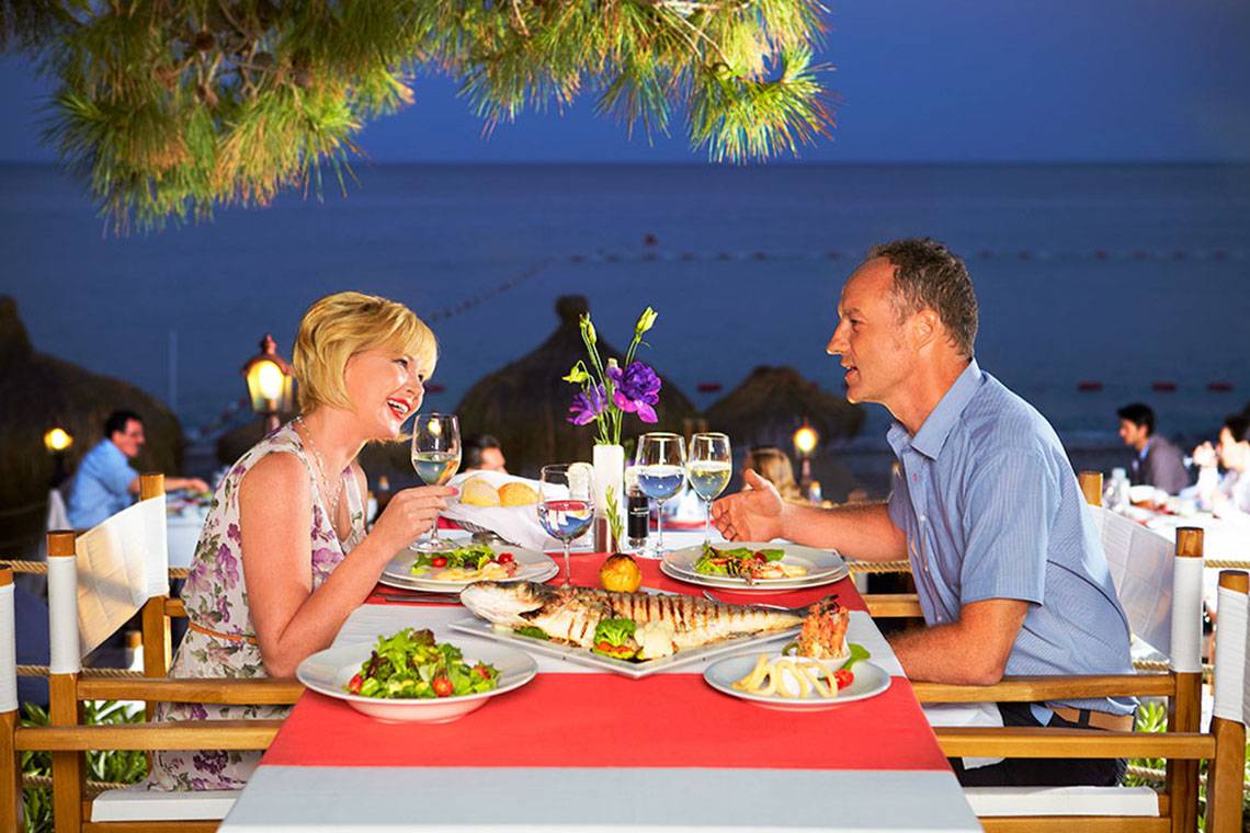 Paar genießt ein Abendessen im Garten des Hotels Marti Myra mit Blick auf das Meer.