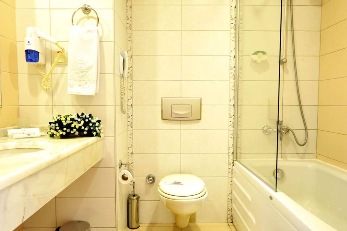 Badezimmer im Titan Select Hotel mit Badewanne, Toilette und Waschbecken.