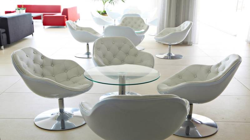 Lobby des Dome Beach Hotel & Resort mit weißen Sesseln und einem Glastisch