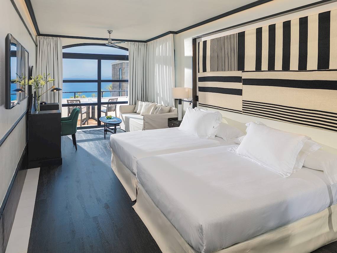 Doppelzimmer mit Meerblick im H10 Rubicon Palace Hotel mit zwei Betten, einem Schreibtisch und einem Sofa.