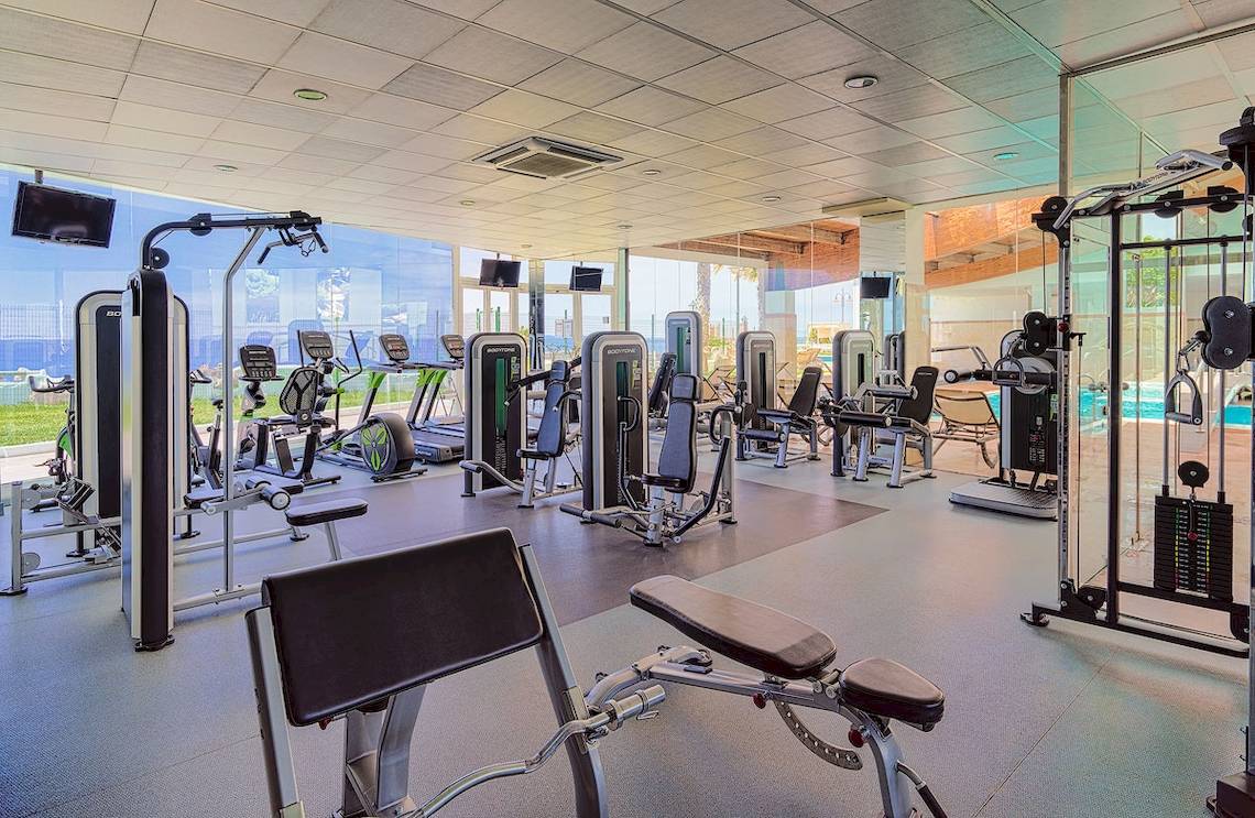 Fitnesscenter im H10 Rubicon Palace Hotel mit modernen Trainingsgeräten und einem Ausblick auf das Schwimmbad.