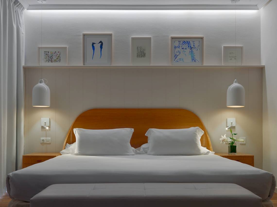 Schlafzimmer im H10 Rubicon Palace Hotel mit weißem Bett, Kissen, Nachttischen und Kunstwerken an der Wand.