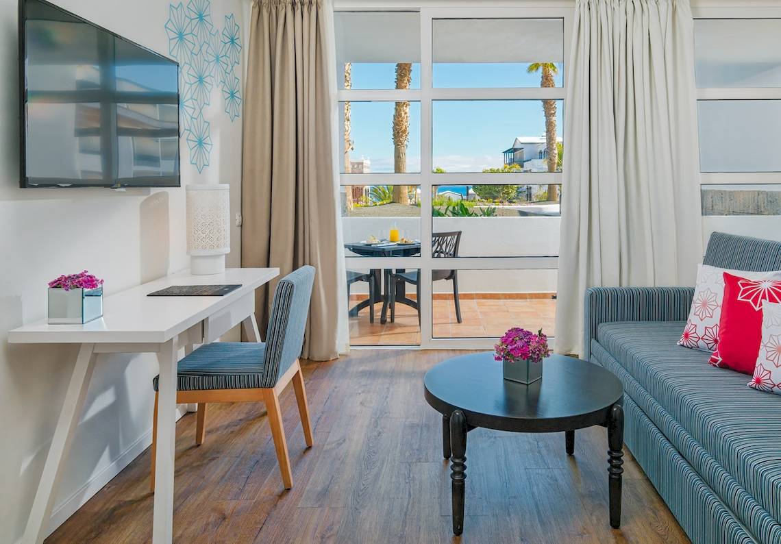 Innenraum des H10 Rubicon Palace mit Arbeitsbereich, Couch und Tisch.