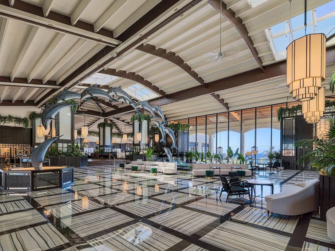 Die Lobby des H10 Rubicon Palace mit Delfinskulpturen und modernen Möbeln.
