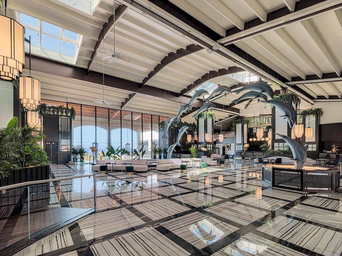 Die Lobby des H10 Rubicon Palace Hotels mit schwarzen und weißen Fliesen und einer hohen Decke mit Delphinen.