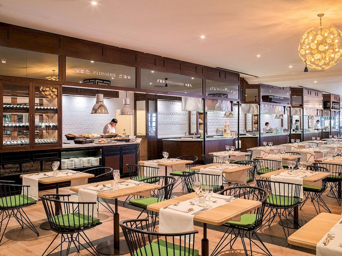 Innenansicht des Restaurants im H10 Rubicon Palace mit Tisch und Stühlen, Theken und Angestellten.