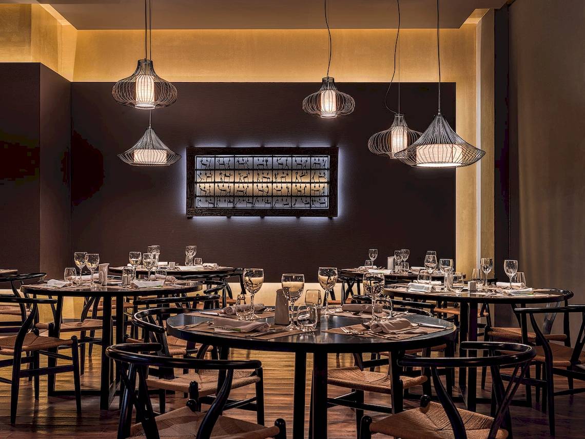 H10 Rubicon Palast Restaurant Innenraum mit Tisch und Stühlen, goldenen Lampen und Wandkunst.