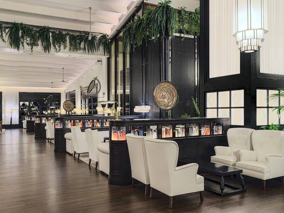 Innenansicht des H10 Rubicon Palace Hotels, Loungebereich mit weißen Sesseln, Bücherwand und schwarzem Tisch.