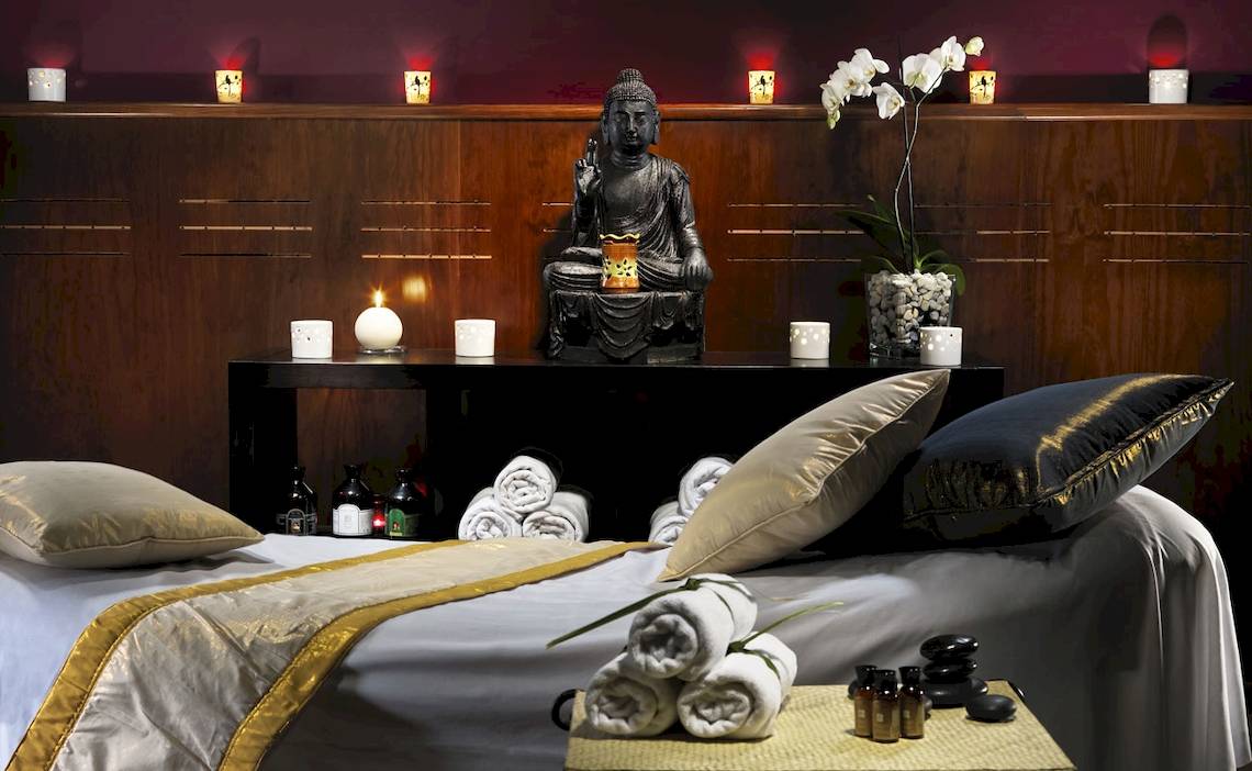 Wellnessbereich im H10 Rubicon Palace Hotel mit einem Bett, Kissen, Buddha-Statue und Kerzen