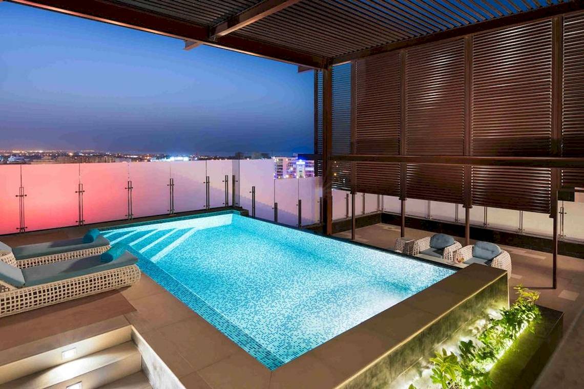 Ein Swimmingpool auf der Dachterrasse des Grand Millennium Muscat Hotels bei Nacht