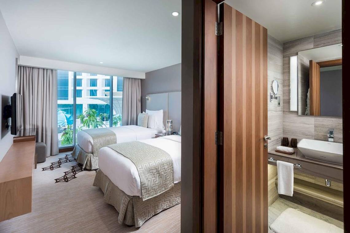 Doppelbettzimmer im Grand Millennium Muscat Hotel mit Blick auf die Stadt.