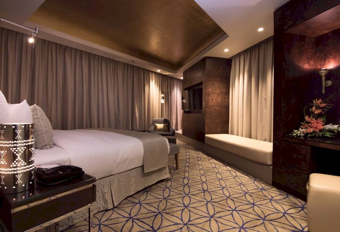 Schlafzimmer im Grand Millennium Muscat Hotel mit Bett, Sitzecke und Dekor