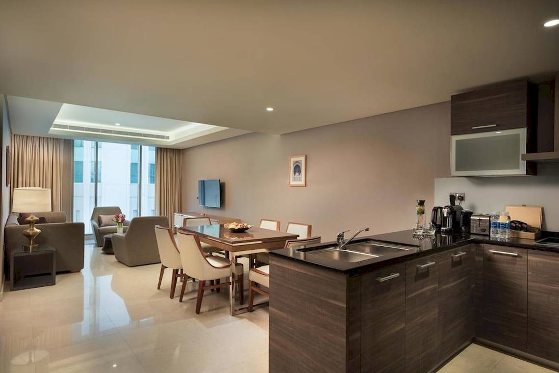 Suite-Wohnzimmer im Grand Millennium Muscat mit Esstisch und Sofas.