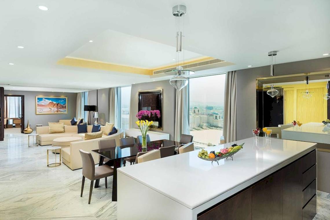 Wohnbereich im Grand Millennium Muscat Suite mit moderner Einrichtung und Ausblick auf die Stadt.