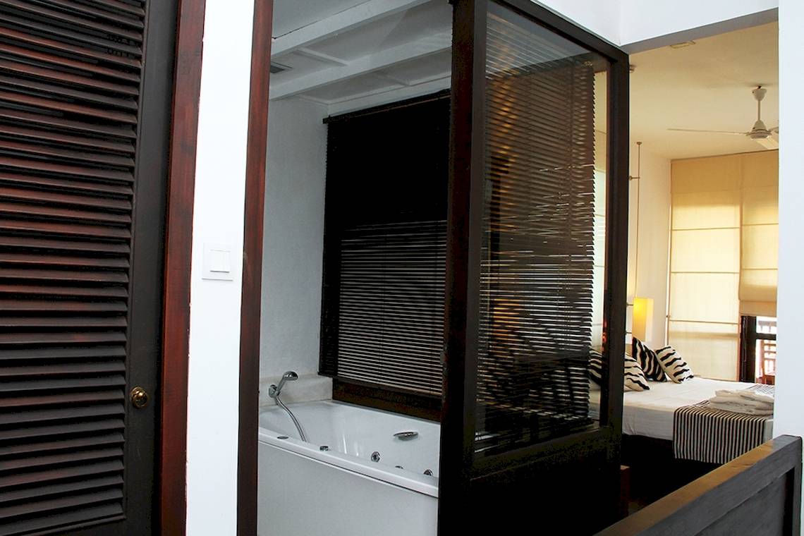 Zimmer im Goldi Sands Hotel mit Badewanne im Freien, teilweise durch eine Glastür verdeckt.