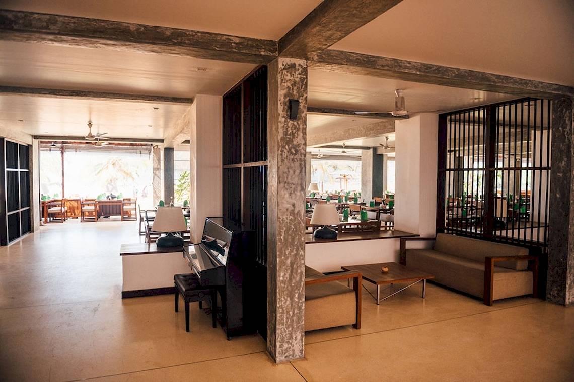 Innenansicht der Lobby im Goldi Sands Hotel mit Klavier, Sofas und Tischen.