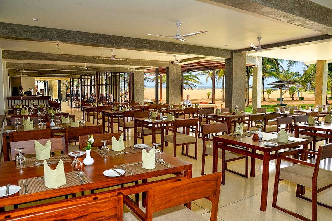 Innenbereich des Goldi Sands Hotel Restaurants mit Blick auf das Meer und Palmen