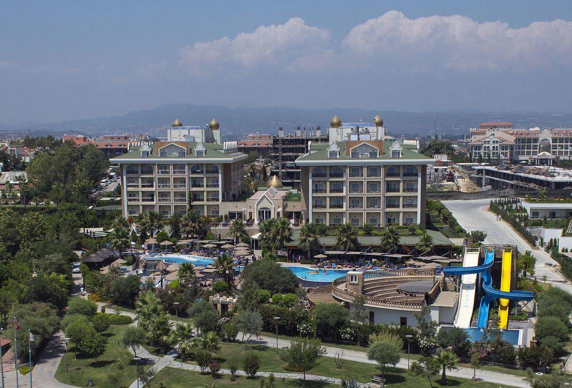 Luftaufnahme des Adalya Bliss Hotels mit Pools, Wasserrutschen und umgebenden Bäumen.