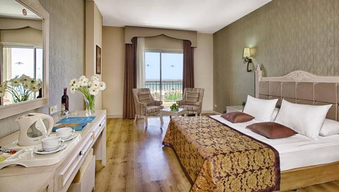 Innenansicht eines eleganten Hotelzimmers im Adalya Bliss Hotel mit Blick auf den Balkon.
