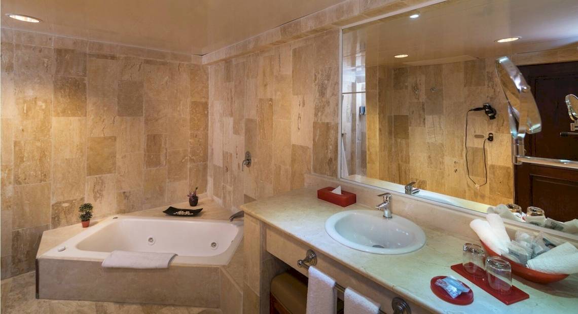 Ein Badezimmer mit Badewanne und Spiegel im Occidental Caribe Hotel