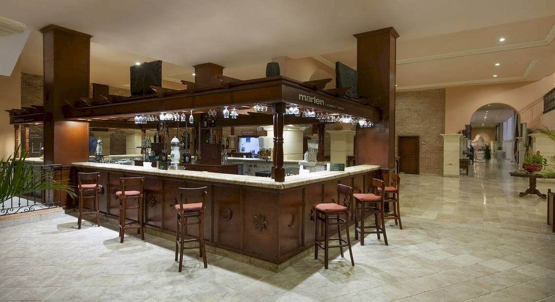 Die Lobby-Bar des Occidental Caribe Hotels mit Holzbar, Stühlen und Fernseher.