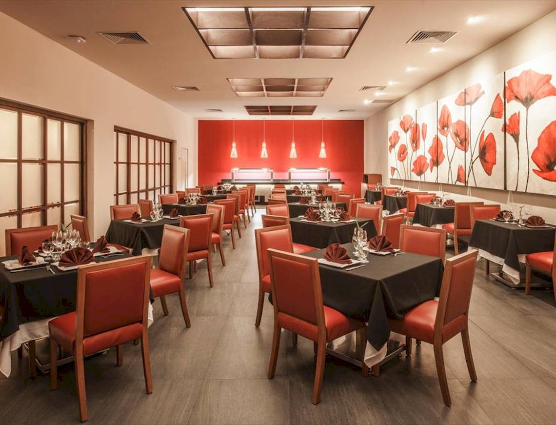 Innenbereich des Allegro Playacar Restaurants mit roten Stühlen und Tischen, rote Wand und rote Blumenbilder.