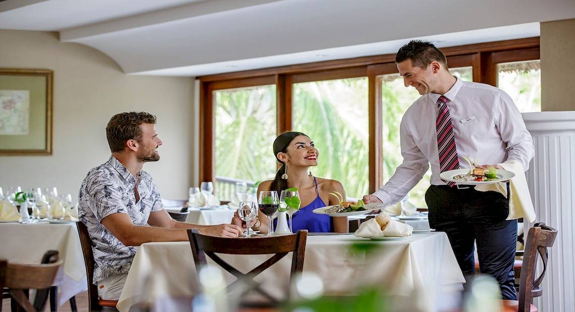 Ein Kellner serviert ein Paar im Allegro Playacar Hotel Restaurant.