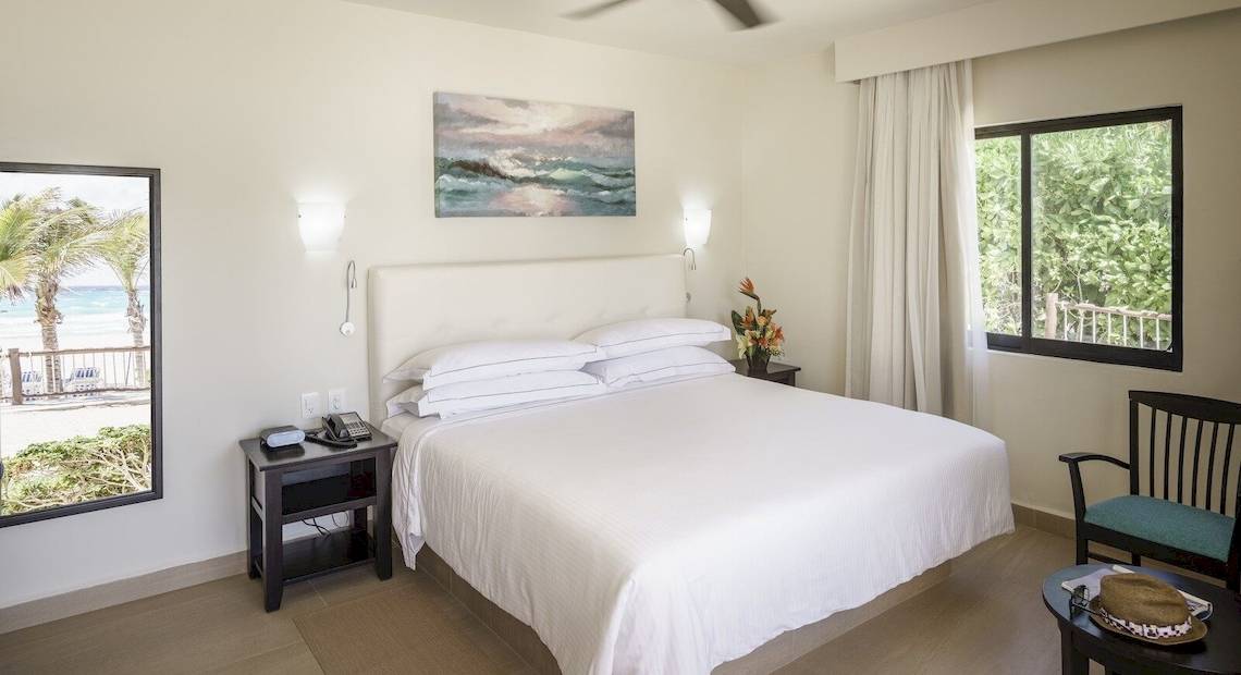 Schlafzimmer im Allegro Playacar Hotel mit Blick auf den Ozean und Möbeln.