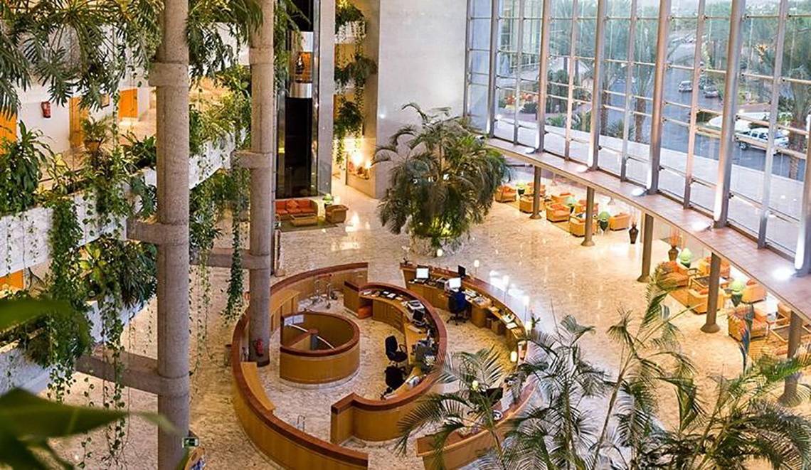 Empfangshalle des Maspalomas Princess Hotels mit Rezeption und grünen Pflanzen.