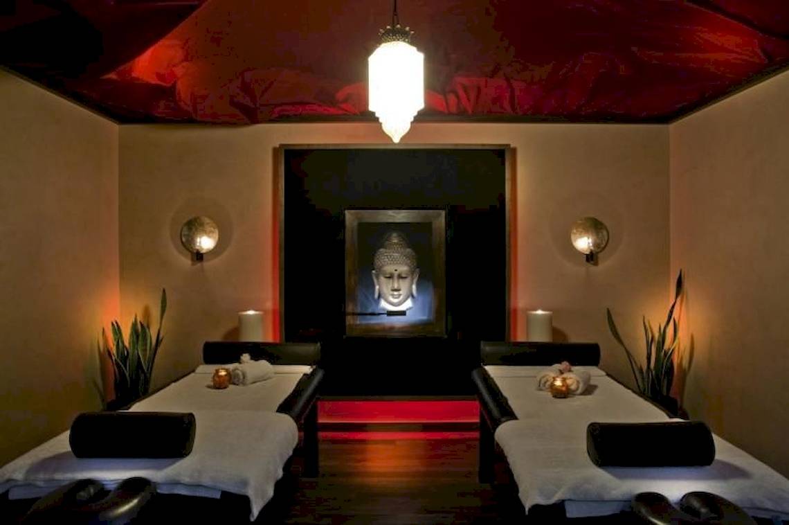 Massageraum im Elite Suites by Rhodes Bay mit zwei Massagetischen, Buddha-Bild und roten Akzentbeleuchtung.