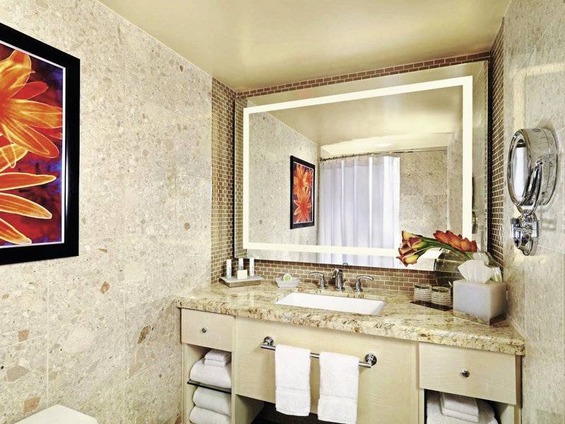 Das Badezimmer im Mirage Hotel & Casino mit einer großen Spiegelwand, einem Waschbecken und einer Toilette.