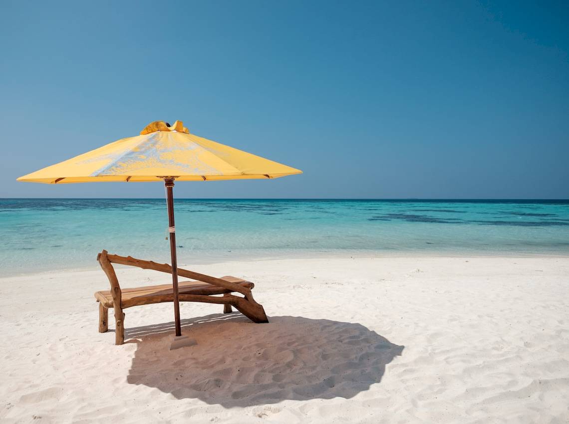 Eine Strandliege mit einem gelben Schirm im Drift Thelu Veliga Retreat