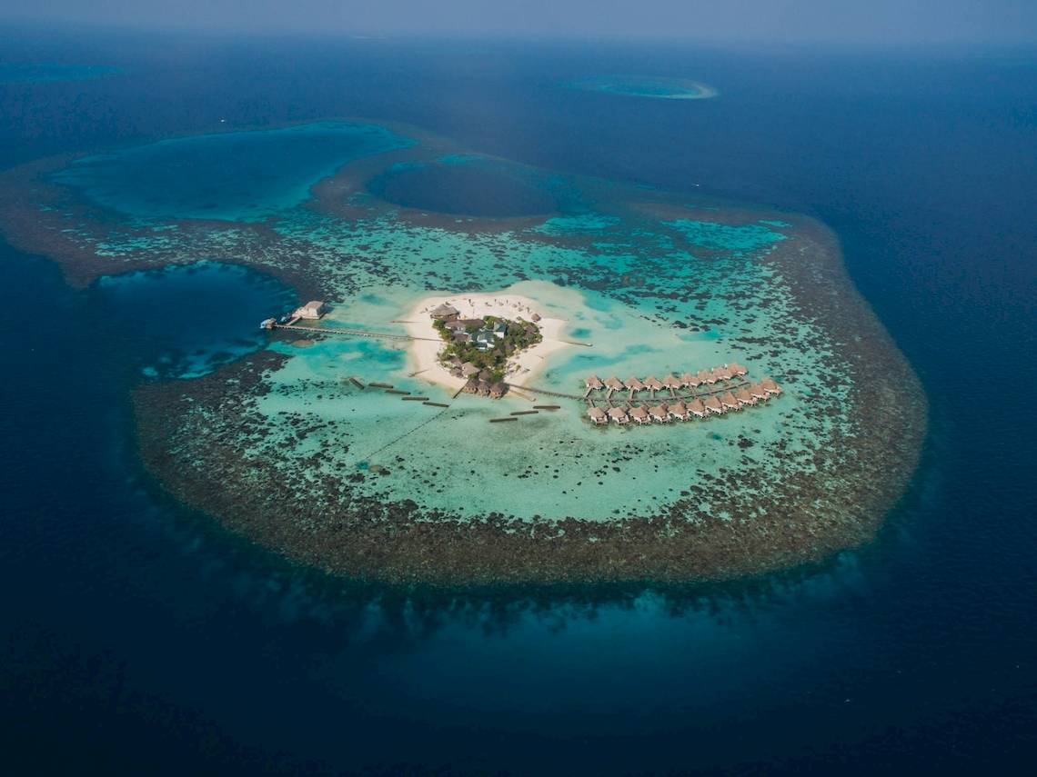 Luftaufnahme des Drift Thelu Veliga Retreat, einer Insel mit vielen Bungalows und einem Steg.