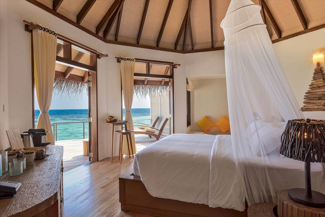 Schlafzimmer im Drift Thelu Veliga Retreat mit Blick auf das Meer und Möbeln auf der Terrasse.