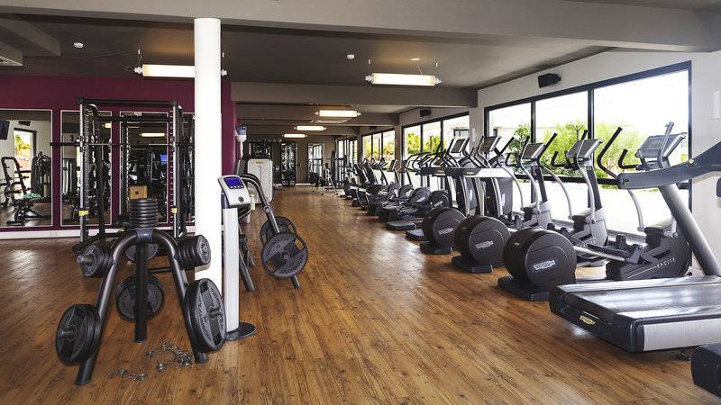 Innenbereich des Fitnesscenters des Papagayo Beach Hotel & Resort Curaçao mit vielen Geräten und Holzboden