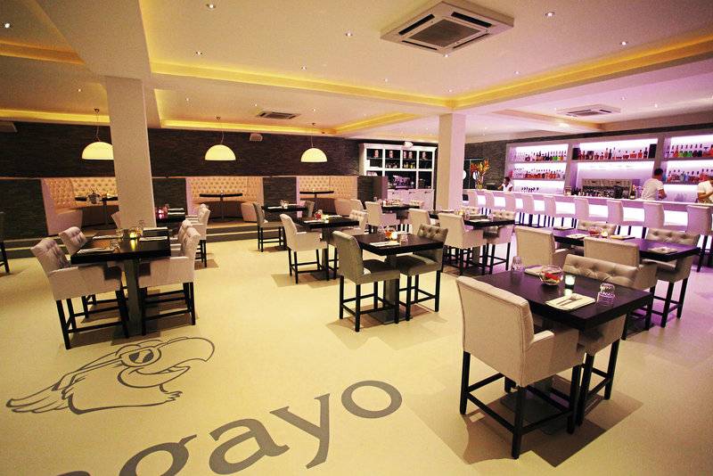 Innenansicht des Restaurants im Papagayo Beach Hotel & Resort Curaçao mit runden Tischen und Stühlen.