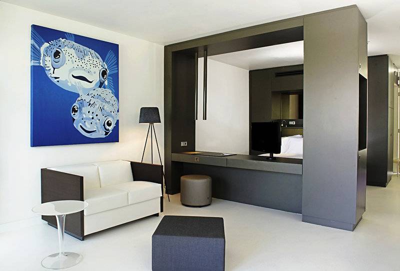 Innenansicht der Suite im Papagayo Beach Hotel & Resort Curaçao mit weißem Sofa, Schreibtisch und Fernseher.