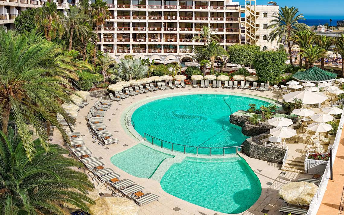 Luftaufnahme des Swimmingpool-Bereichs des Seaside Sandy Beach Hotels mit vielen Liegestühlen und Sonnenschirmen.
