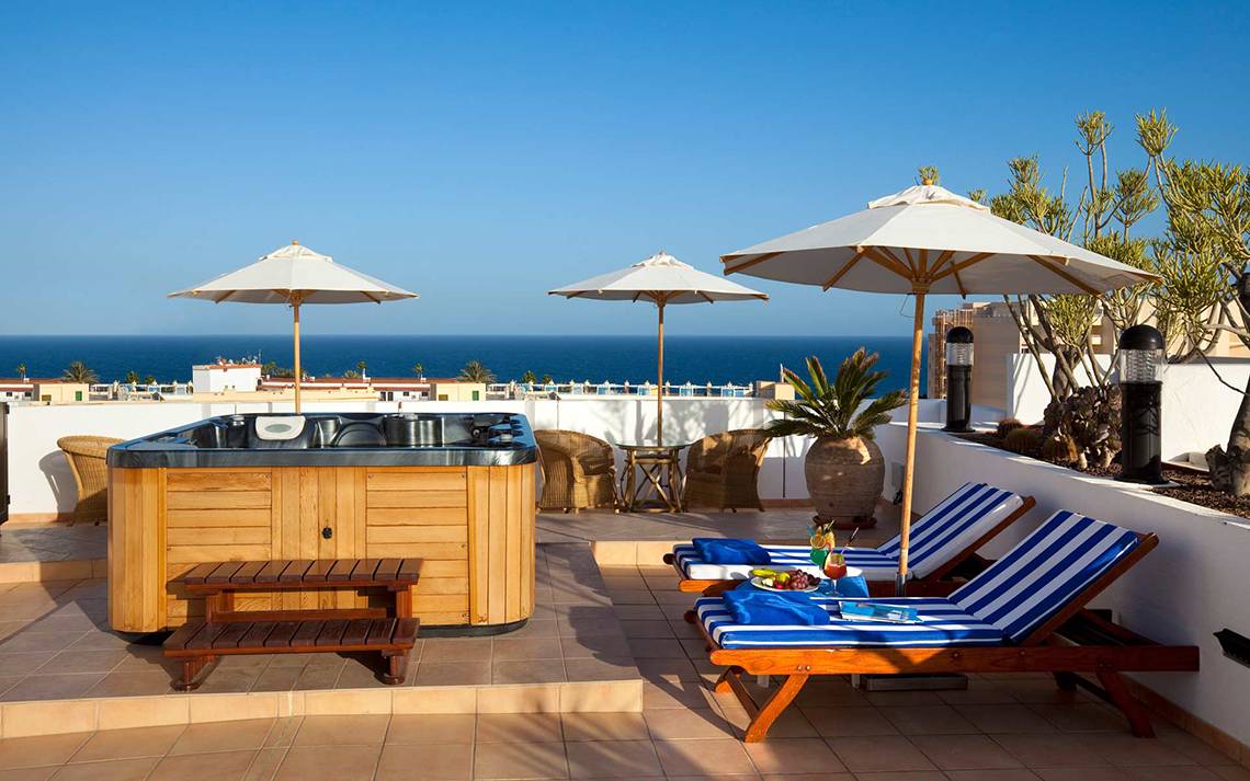 Terrasse im Seaside Sandy Beach Hotel mit Hot Tub und Sonnenschirmen am Meer