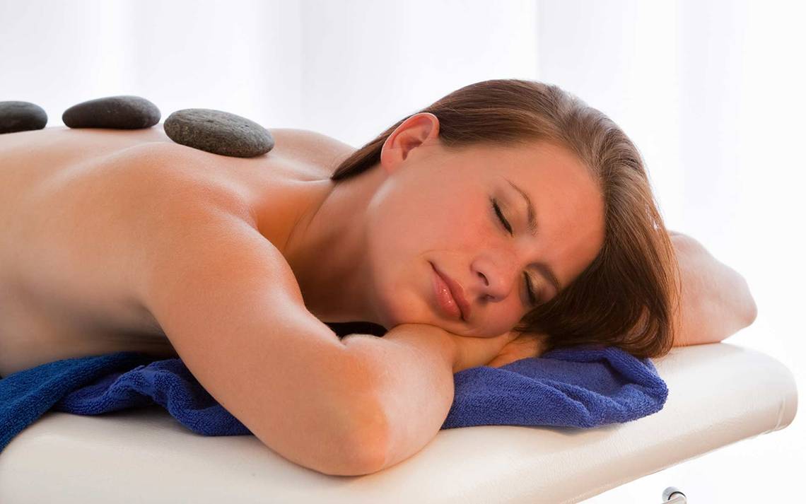 Eine Frau genießt eine Rückenmassage mit Steinen im Seaside Sandy Beach Hotel.
